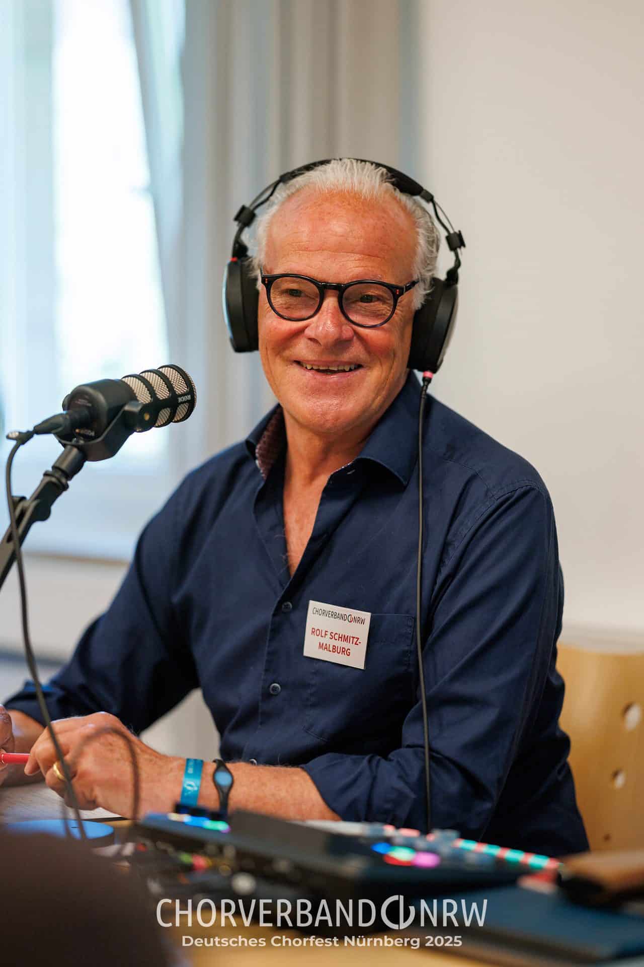 Rolf Schmitz-Malburg am Mikrofon beim Chorcast „Stimmtisch“ des Chorverbands NRW